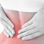 woman holding lower back from coccydynia pain