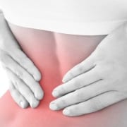 woman holding lower back from coccydynia pain