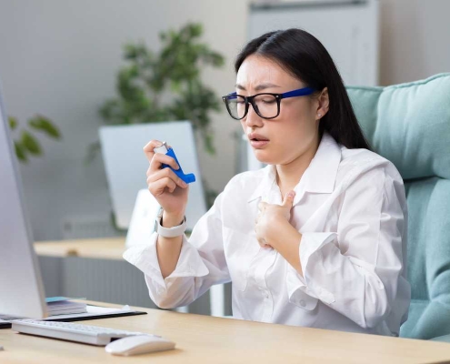 woman with inhaler at desk