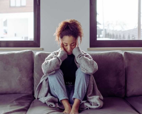 Woman with a migraine on sofa.