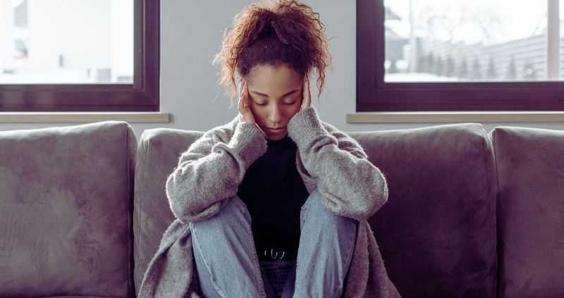 Woman with a migraine on sofa.